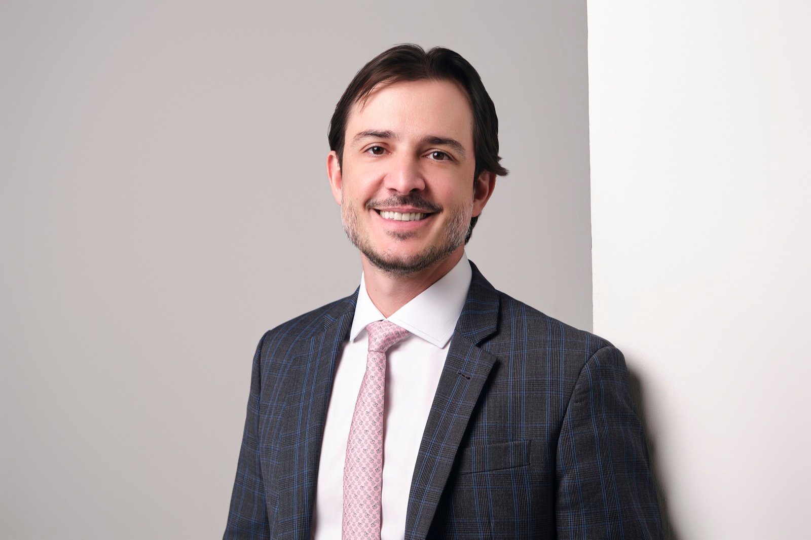 Dr. Guilherme Sella sorrindo, em estúdio